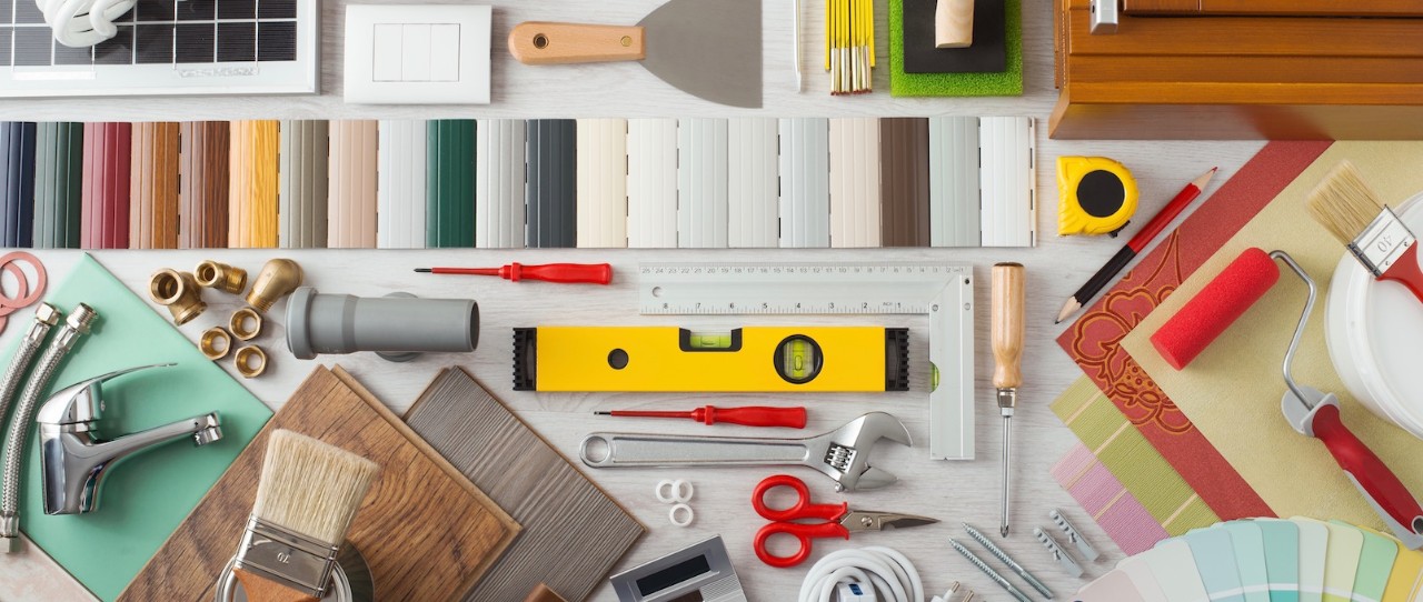 tools on table including ruler, level, paint brush, screwdriver, color samples